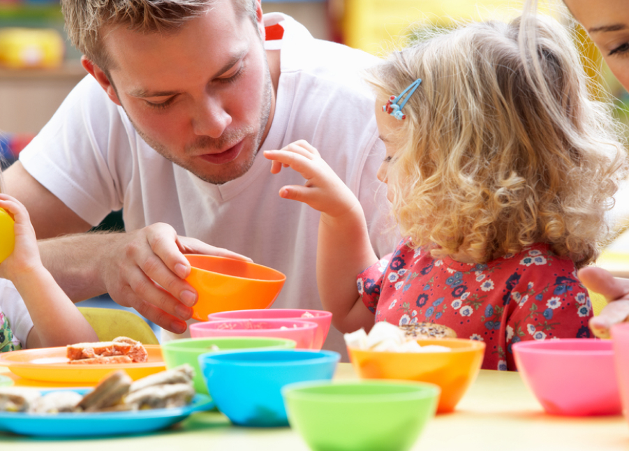 Mann mit gemeinsam spielenden Kindern im Kindergarten